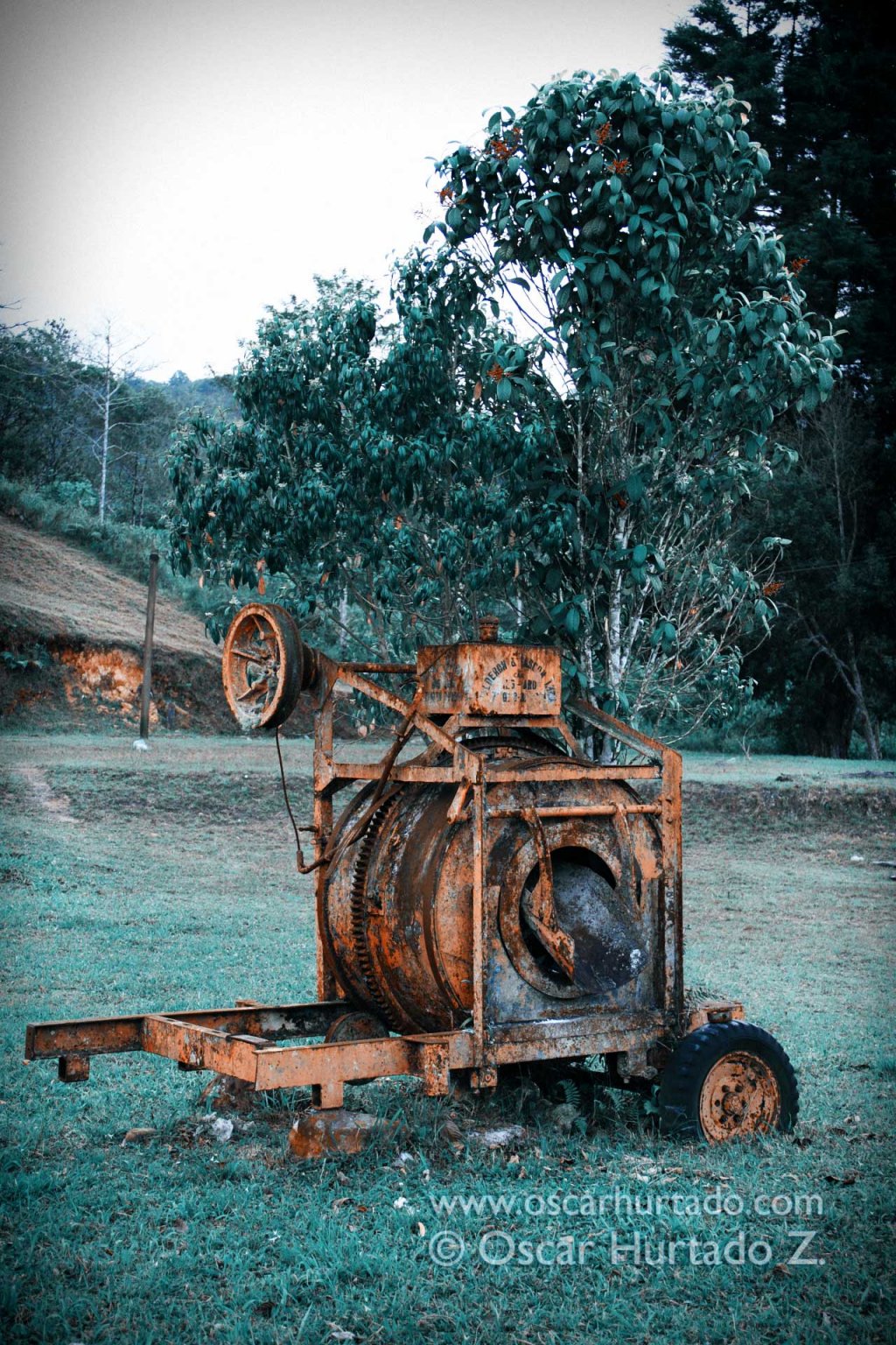 A large corroded and decaying piece of construction equipment lies in the middle of wild plains