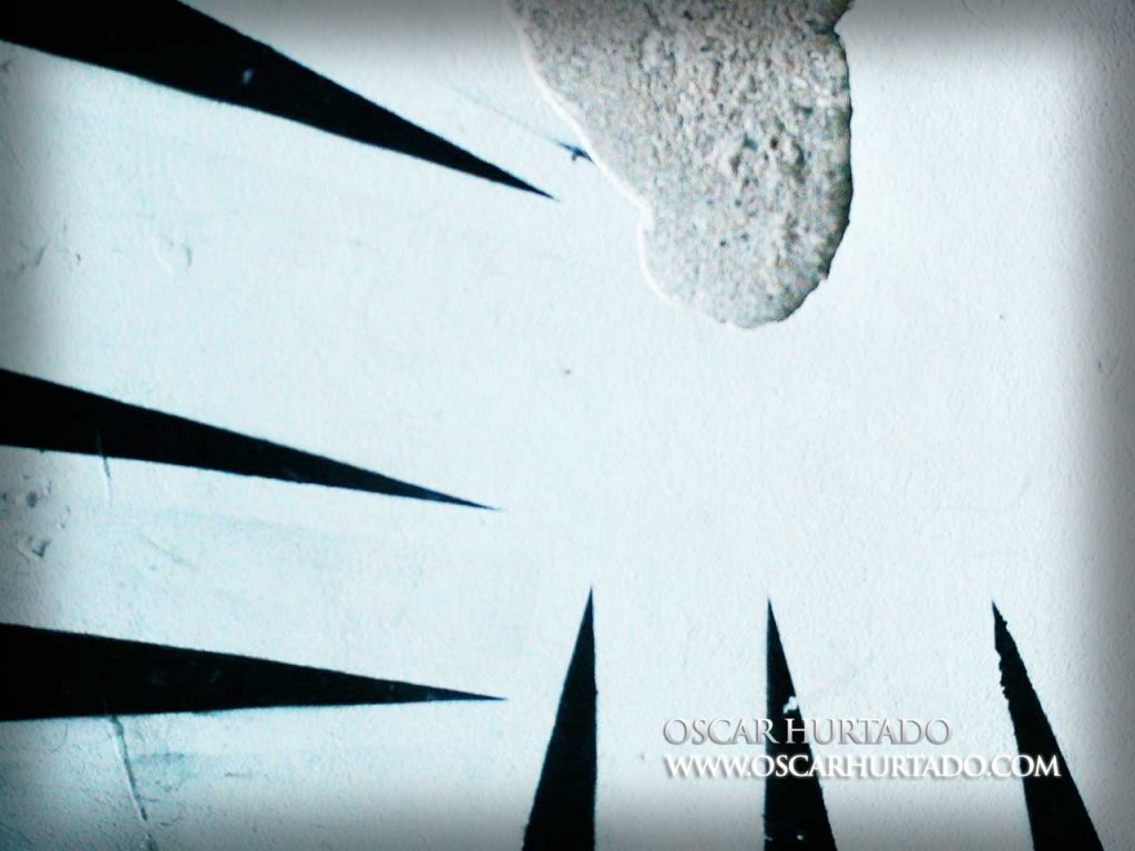 Black graffiti of scratch marks left over an old damaged wall surface