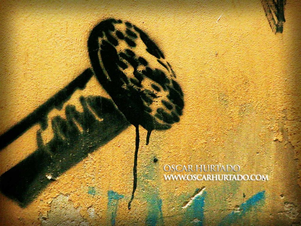 Bold black graffiti of a giant nailhead against an old orange wall surface