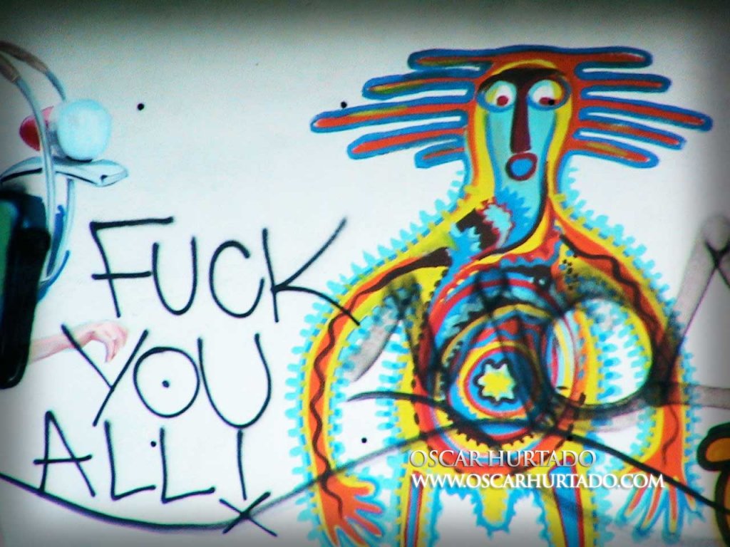 Colorful graffiti portraying a bizarre character lying next to a friendly message