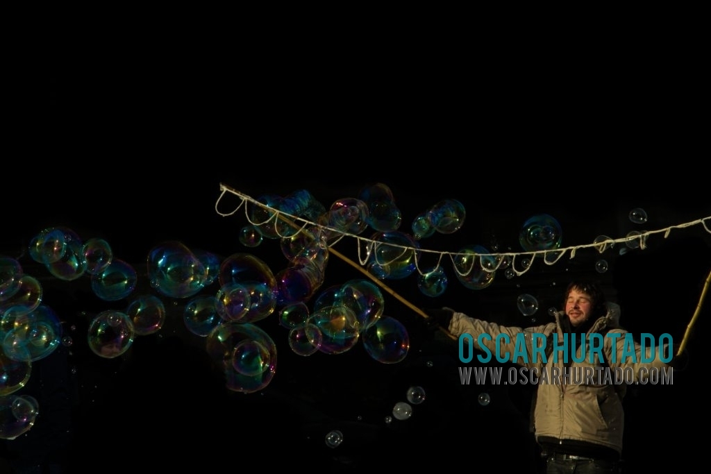 A street artist amuses pedestrians with his giant soap bubbles