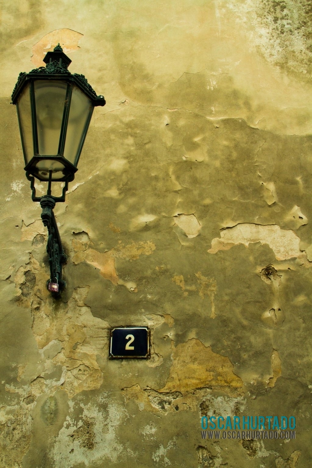 Detail view of an old wall with a lamp and street number