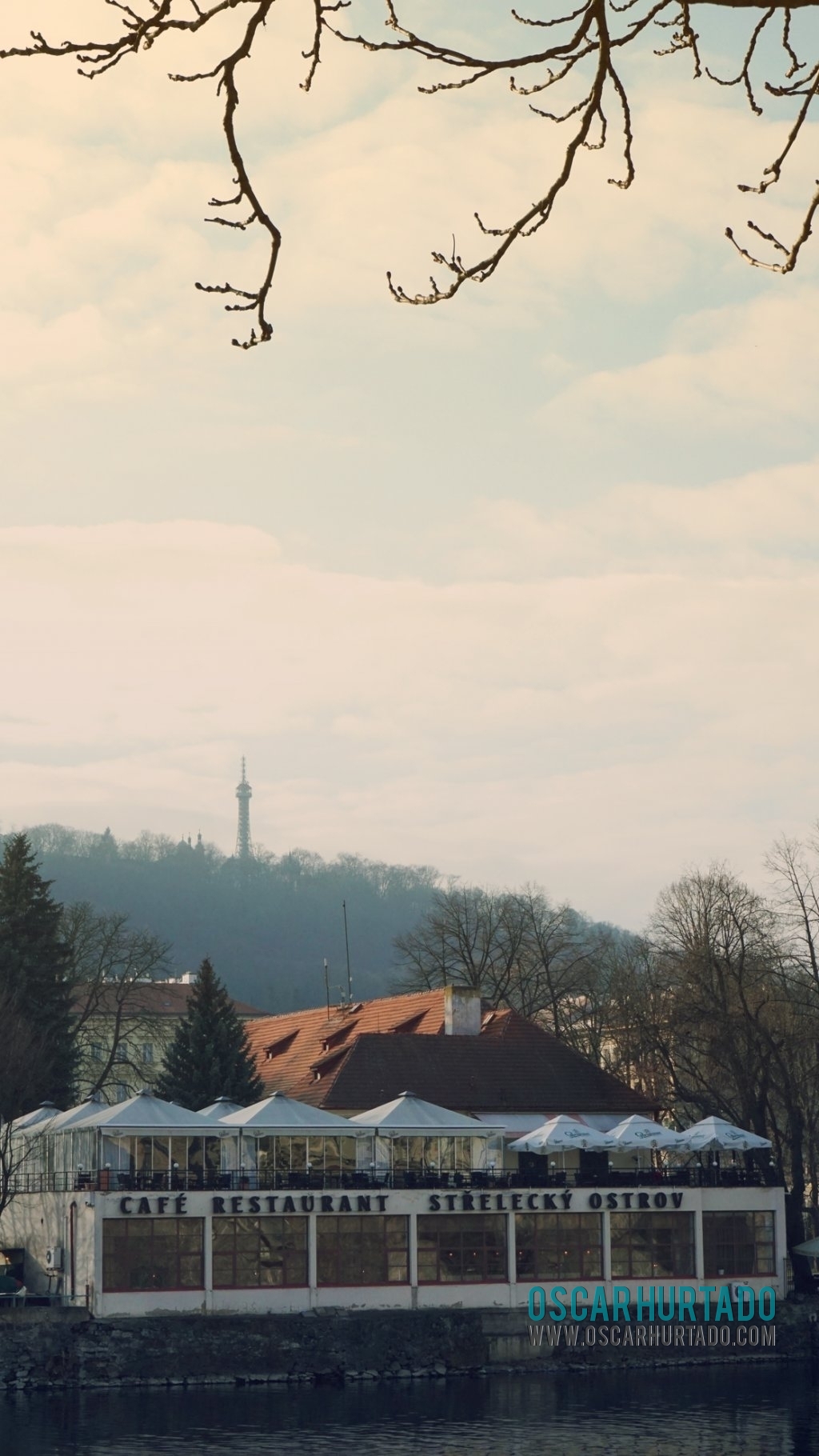 Distant view of a typical boatel located on the shores of Vltava river and contrasting with the Petřín lookout tower on background