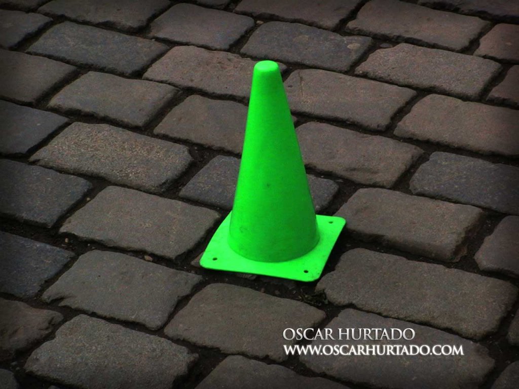 Shot of a bright neon green traffic cone found lying against the stone pavement
