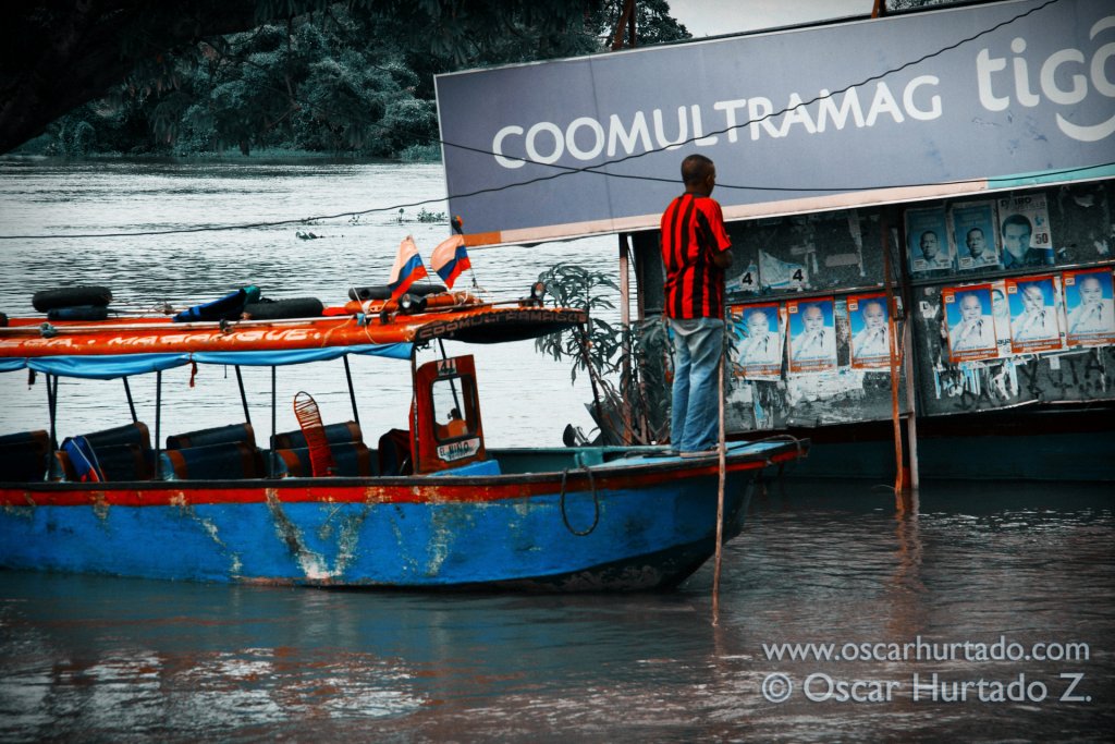 A man leads the way of his colorful boat across the flooded shores of the Magdalena river