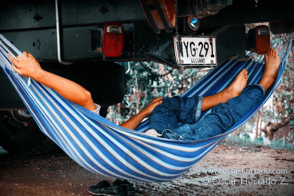 A driver takes a nap on his hammock hanging on the back of his truck while awaiting for permission to transit across the Madgalena River via a ferry